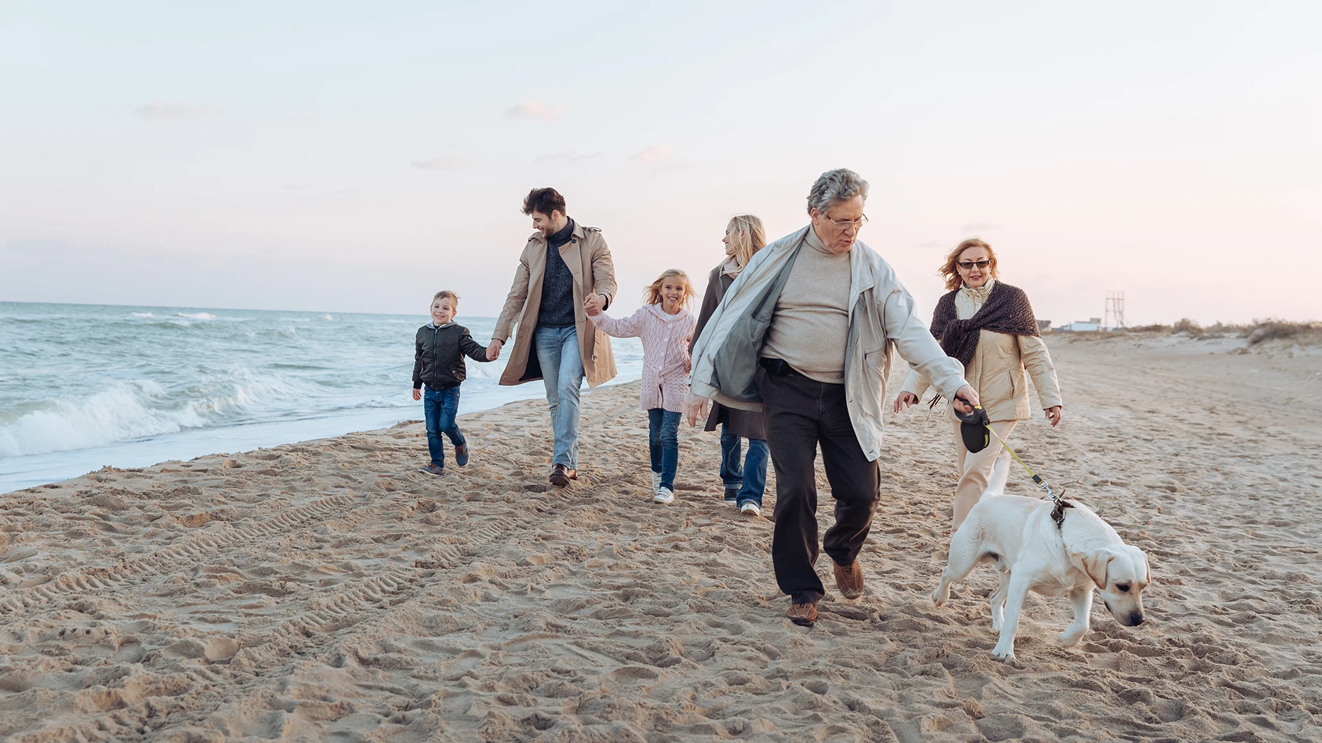 A happy family enjoying their time at the beach with their dog during sunset