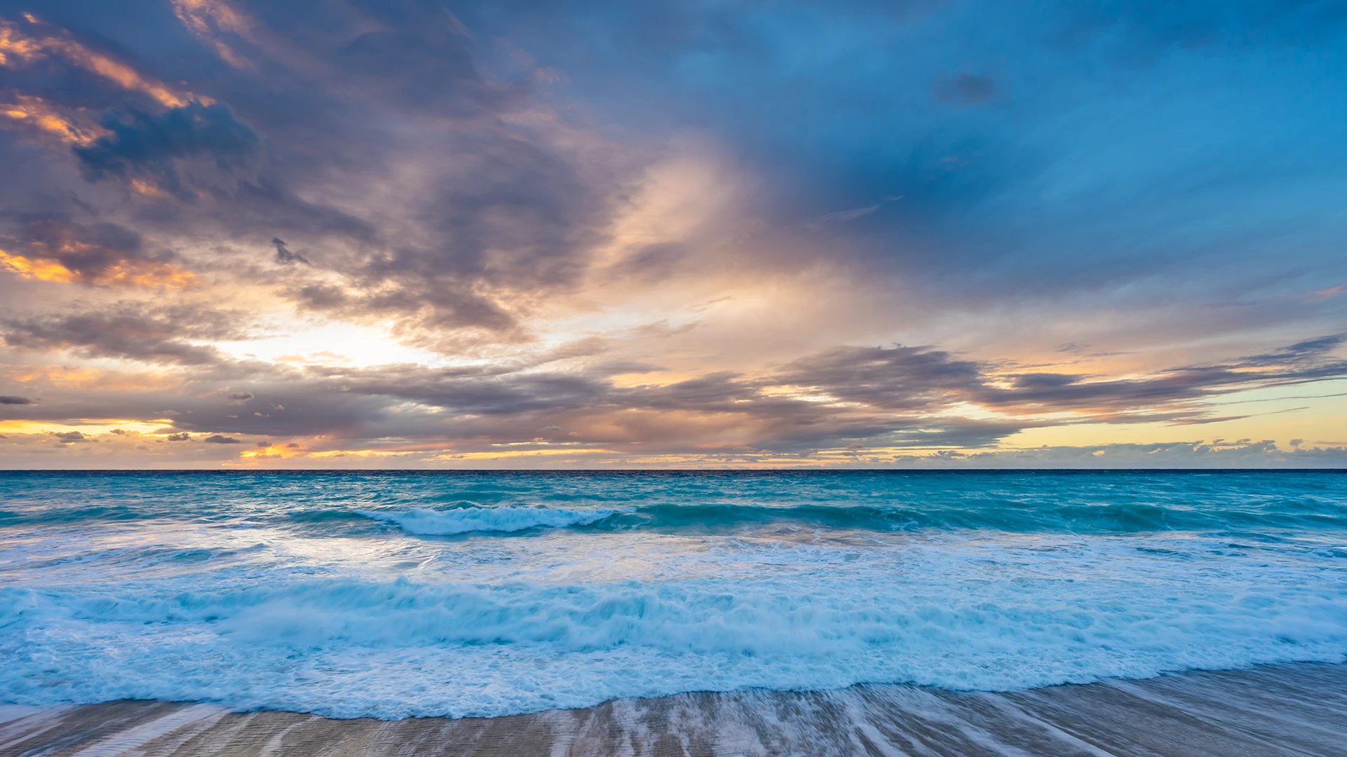 A scenic view of the beach with clear blue water at sunset