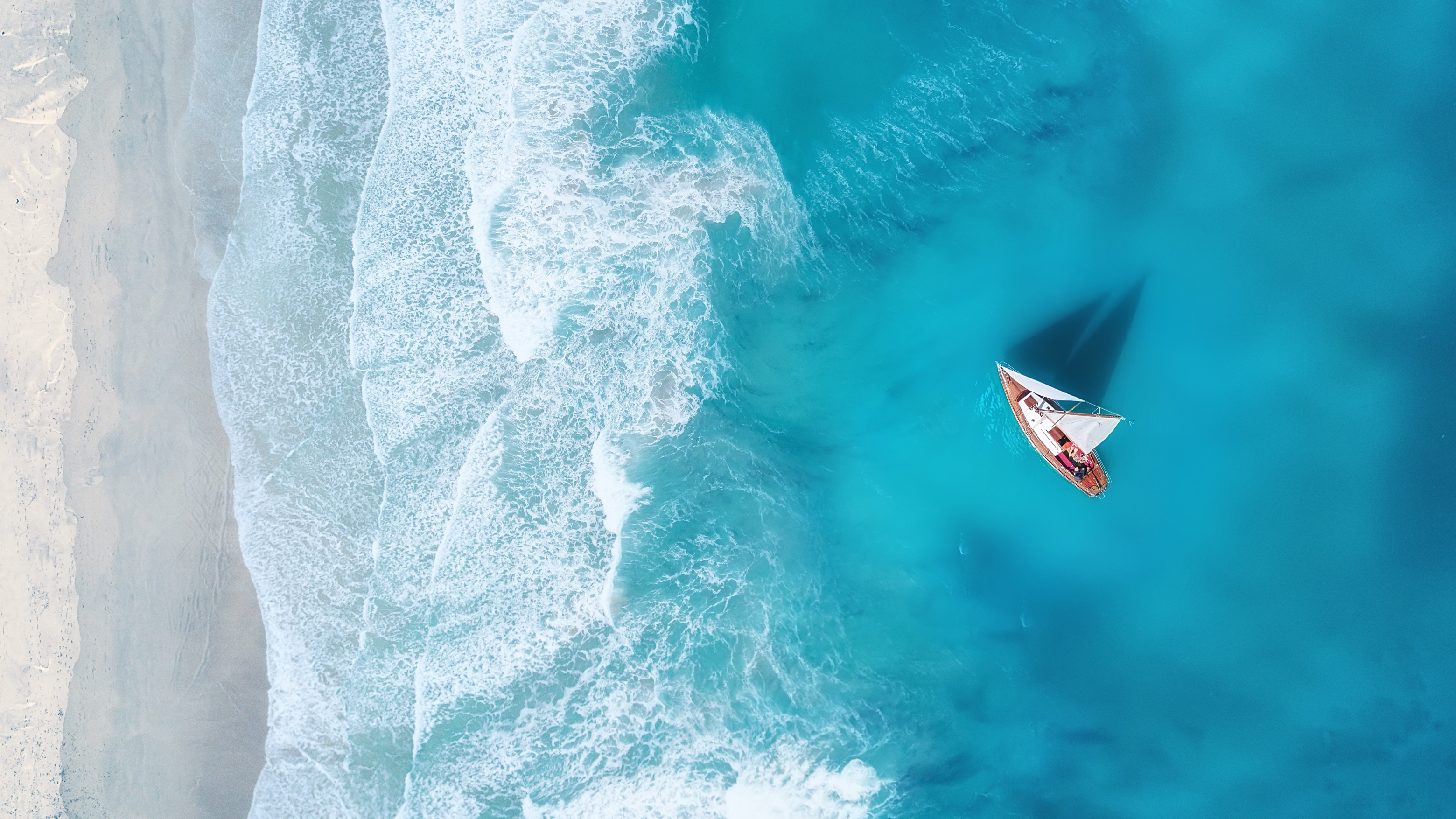 Blog13 Image: Waves crashing gently on the shore while a small sailboat floats by the shore